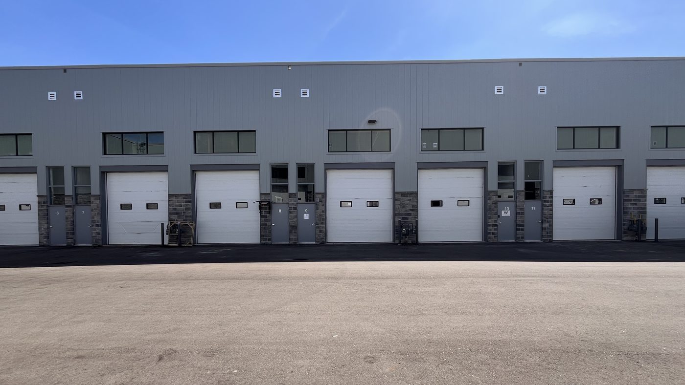 A long row of rental warehouse units on Solar Drive in Mississauga, with overhead doors and grey man doors along the front, seen across the paved yard