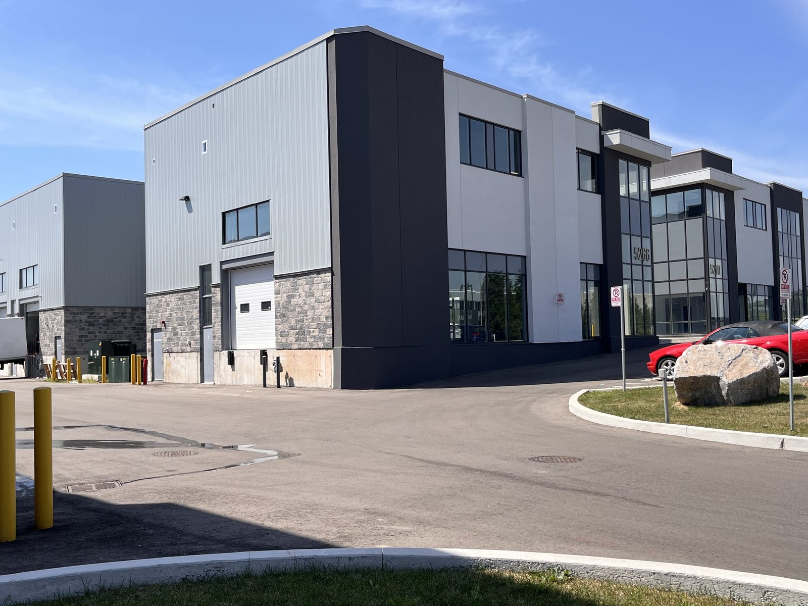 One of the new rental warehouse buildings on Solar Drive in Mississauga, with rows of overhead doors and grey hollow metal man doors along its stone-and-panel front