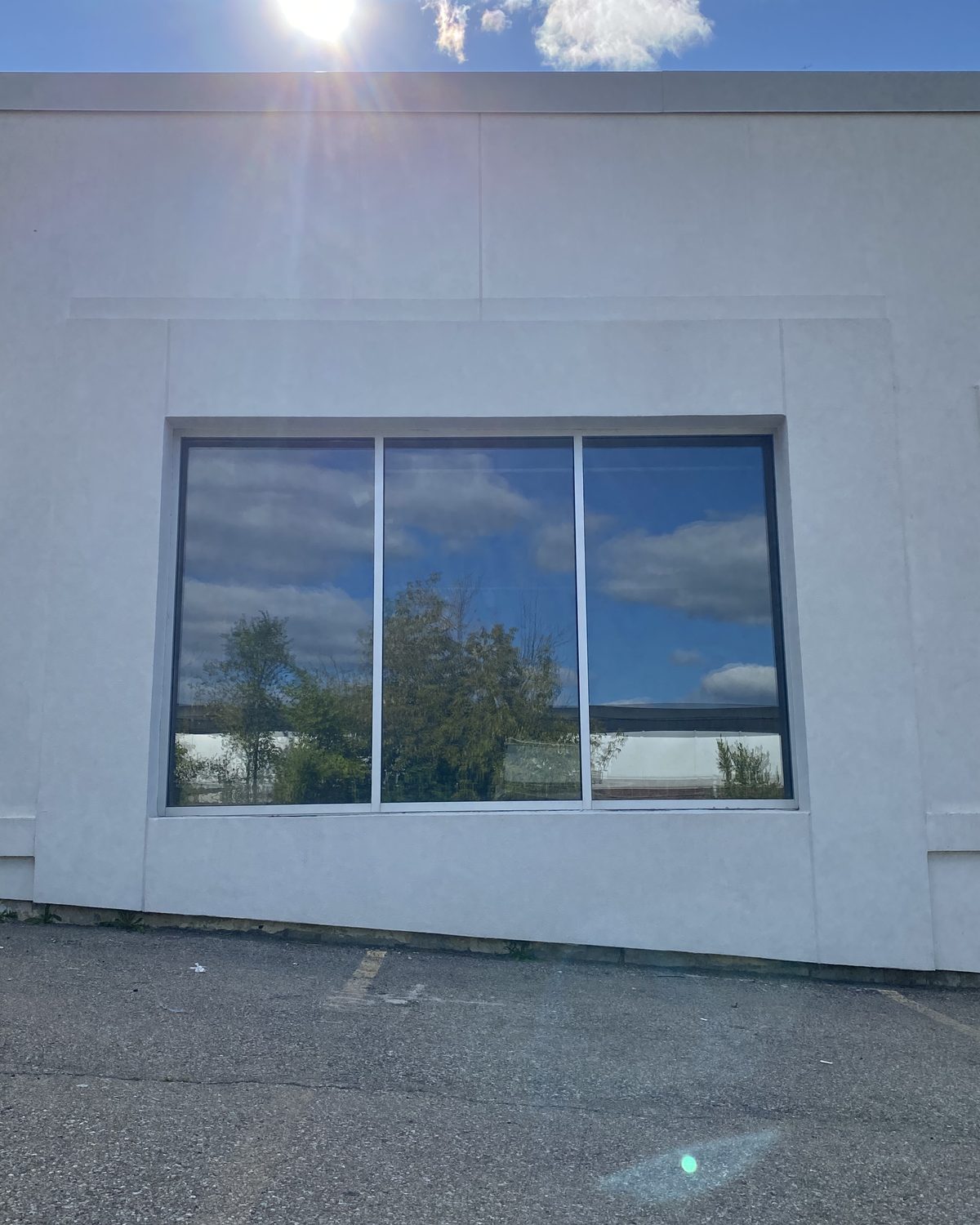A wide new aluminum window with three panes set into the white-rendered wall at 68 Tycos Drive in North York