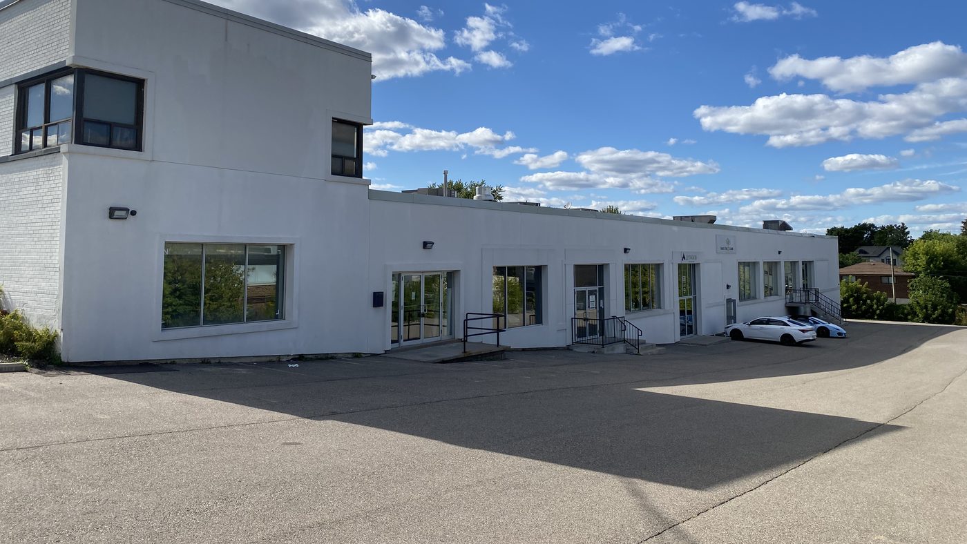 The long, low white building at 68 Tycos Drive in North York, with new windows and entrances along its front and a parking lot in front