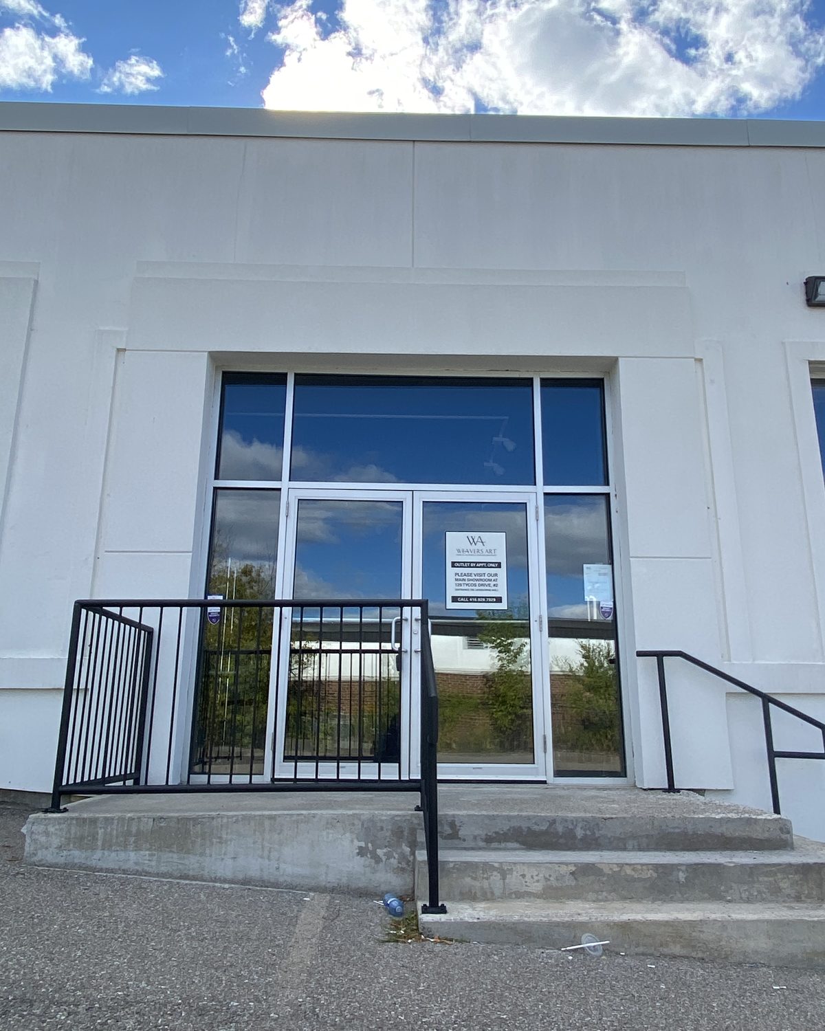 A new glazed aluminum entrance with double doors, a sidelite and a transom, set into the white-rendered wall at 68 Tycos Drive in North York