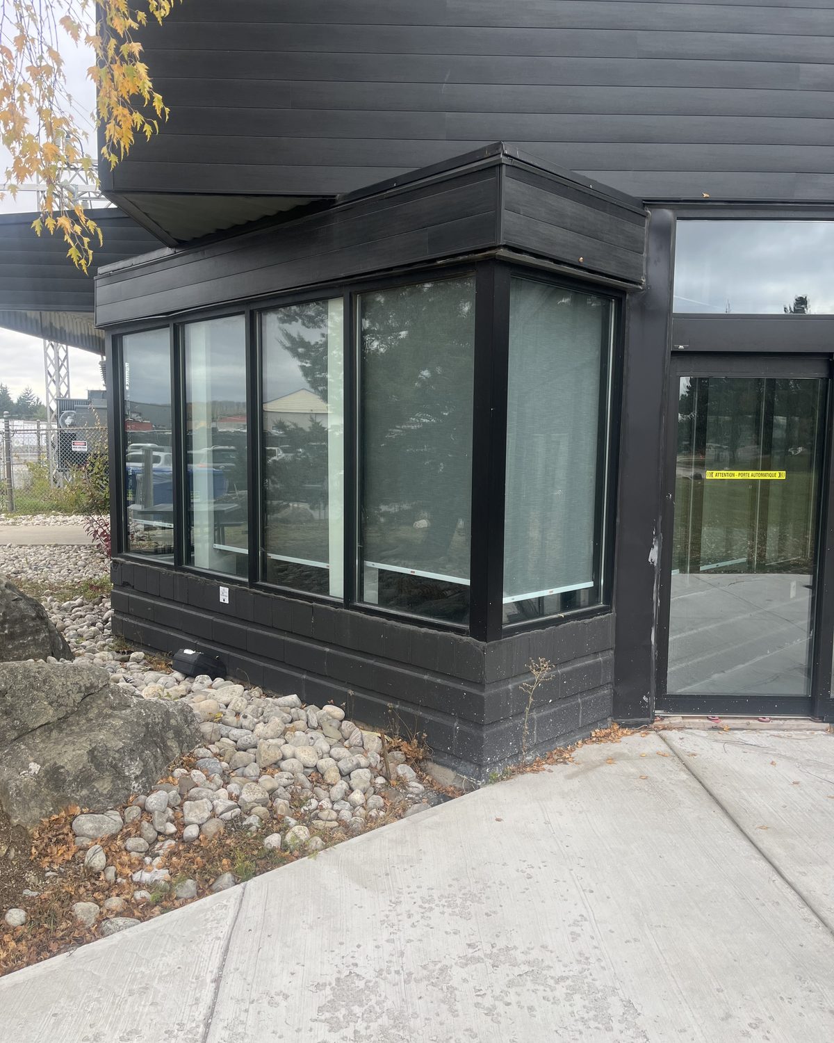 A glazed corner bay in black anodized curtain wall framing on the dark-clad building at 51 Centennial Road in Orangeville