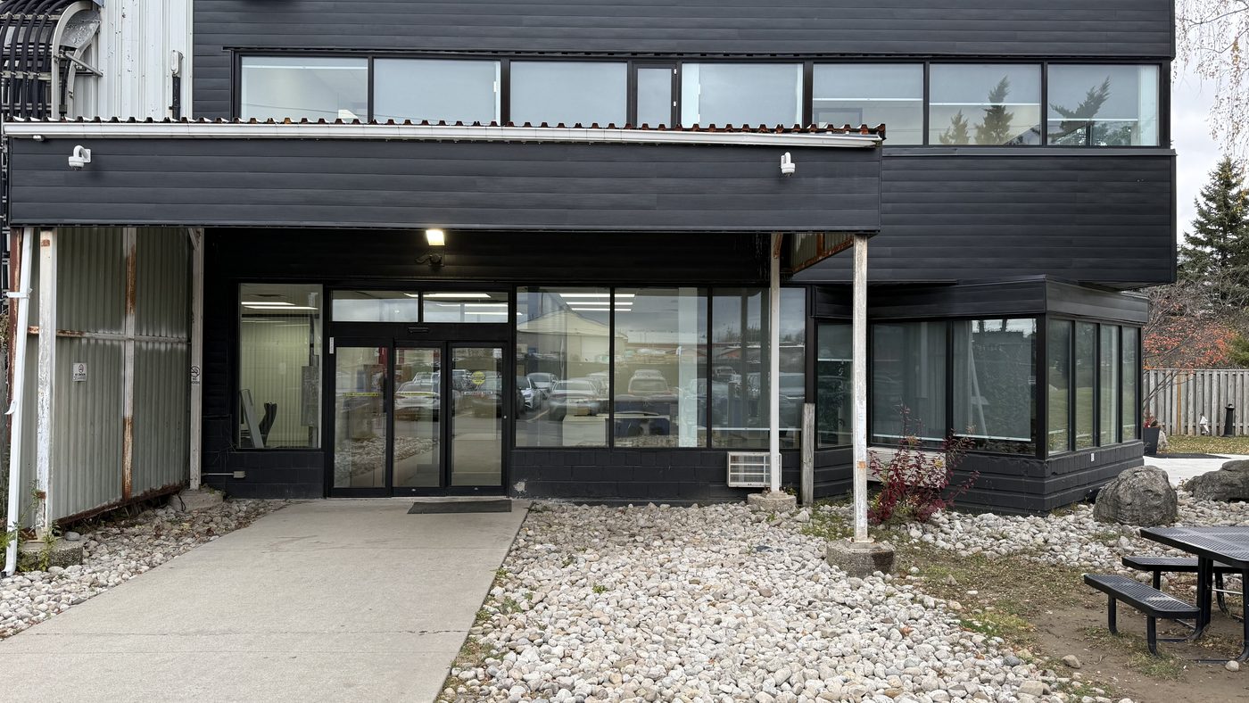 The two-storey dark-clad building at 51 Centennial Road in Orangeville, with black anodized curtain wall glazing across both floors and a canopy over the entrance