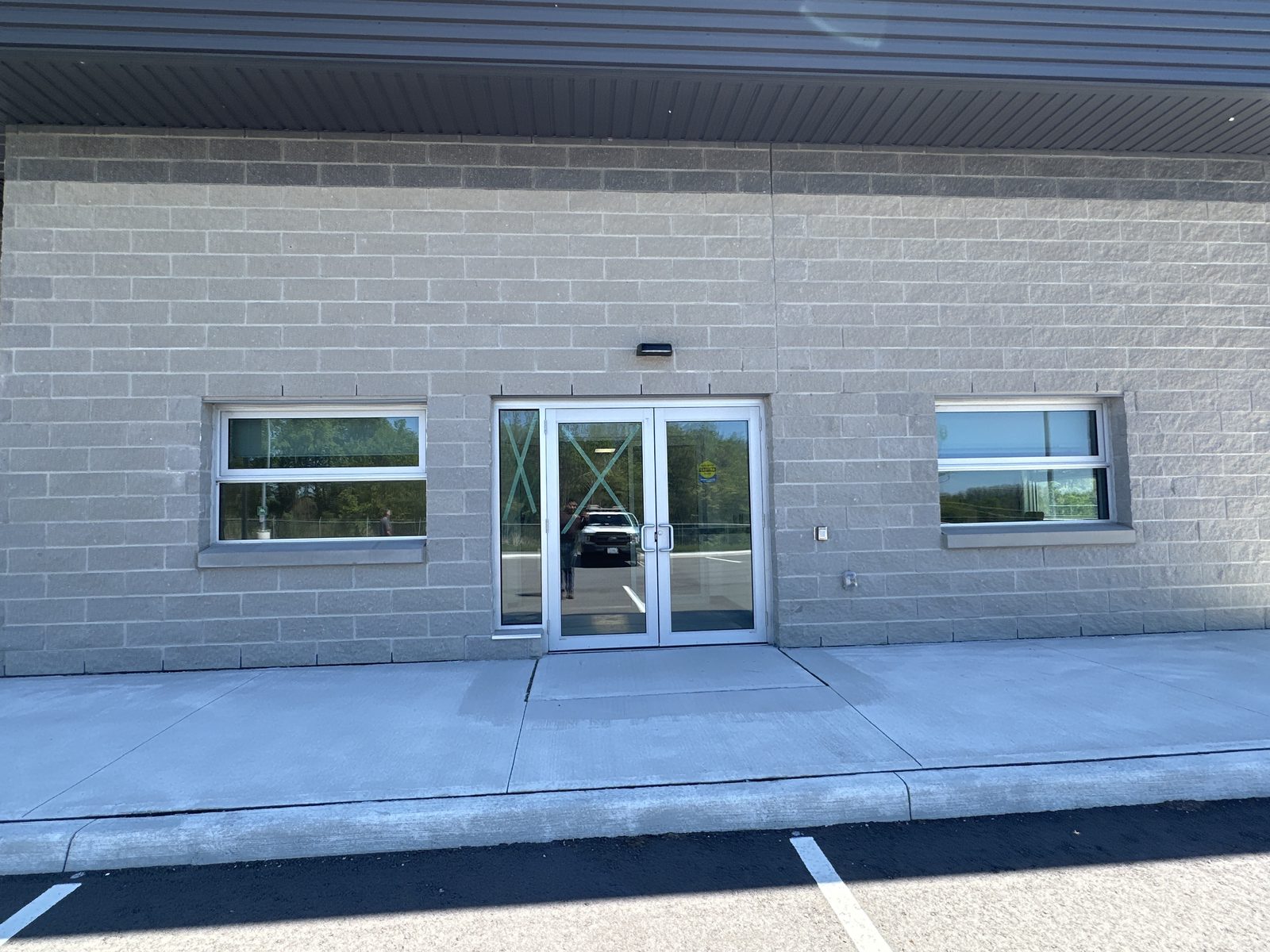 The front of the MTO maintenance patrol yard building at Highways 401 and 418, a grey block building with aluminum windows either side of a glazed double-door entrance, installed by Canuck Door Systems