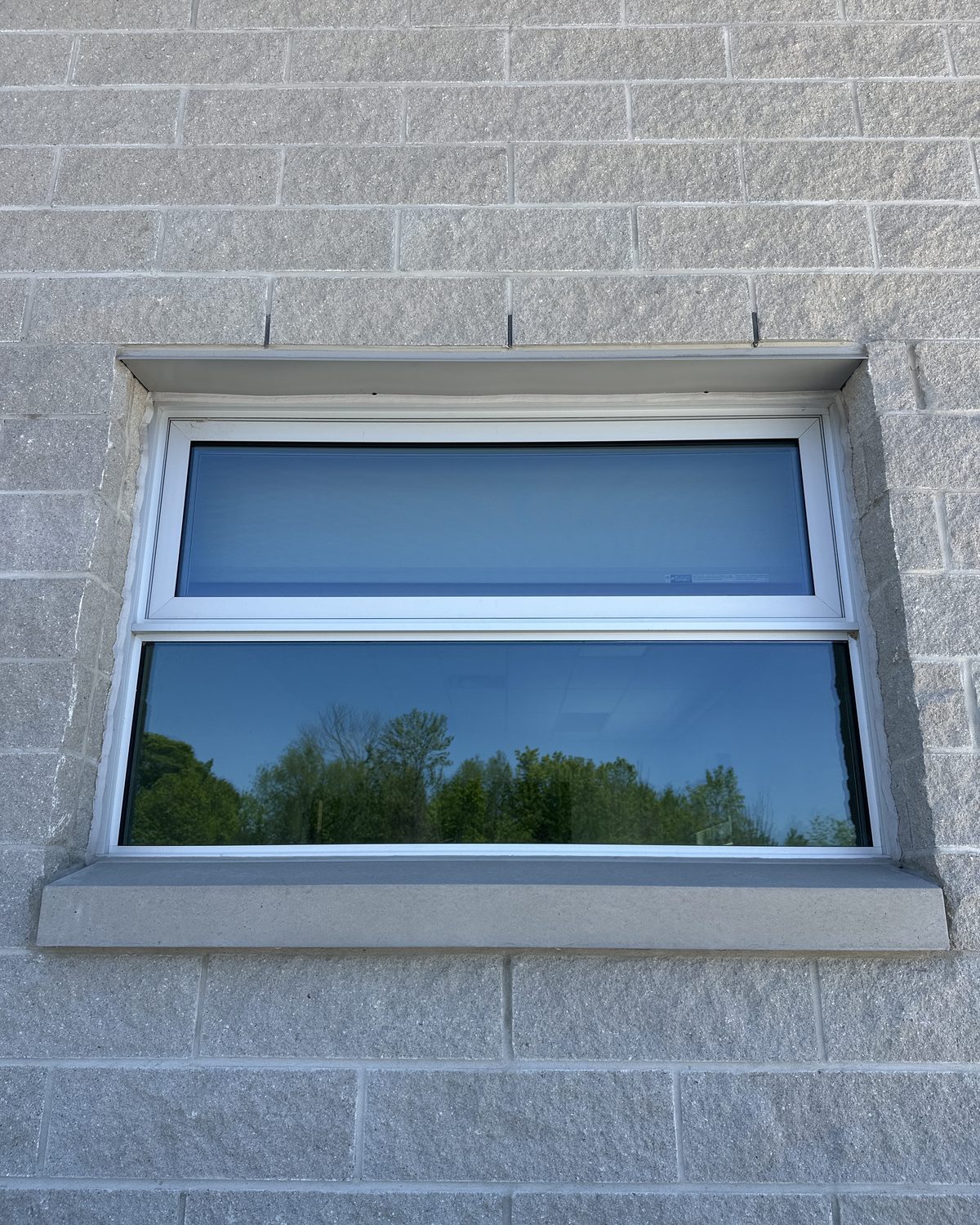 An aluminum window with a lower opening vent set into the grey block wall of the MTO patrol yard building