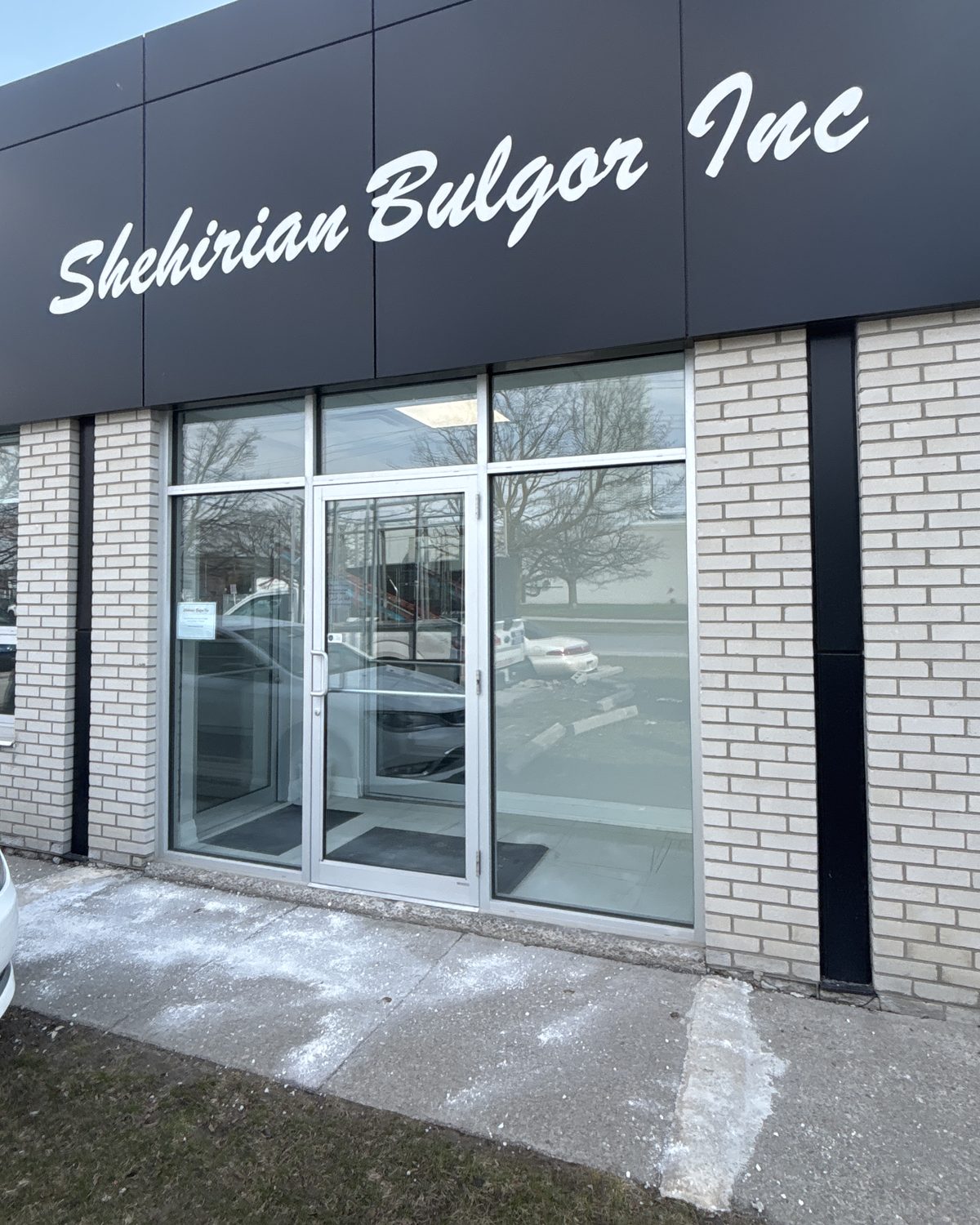 A glazed aluminum storefront entrance with a transom and glazed sidelites, set into light brick under a dark fascia on a commercial building in Scarborough