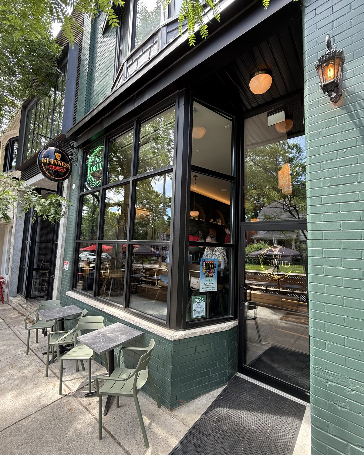 The corner of a painted brick building in Scarborough where a black anodized aluminum storefront turns the corner, with a recessed glazed entrance door beside it