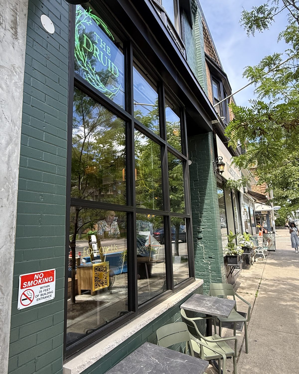 A long run of black anodized aluminum storefront glazing along the side of a painted brick building in Scarborough, seen at an angle along the sidewalk