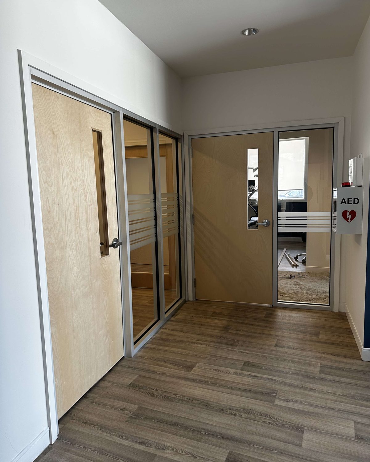 Two natural wood doors with vision panels in aluminum frames with glazed sidelites, inside the Shelburne Dental clinic