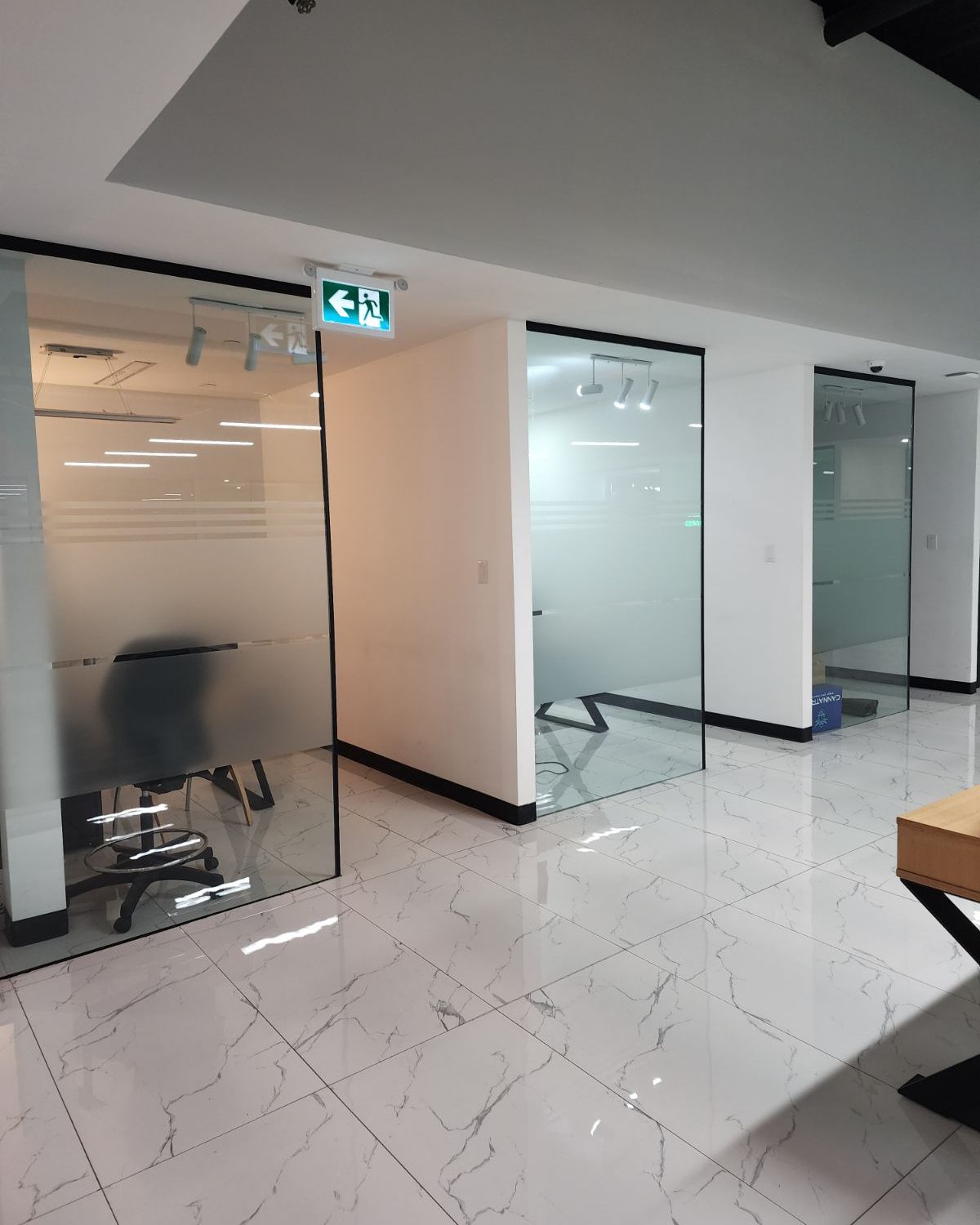 Two glass-walled rooms with frameless glass doors inside the Smoke Arsenal office in Toronto