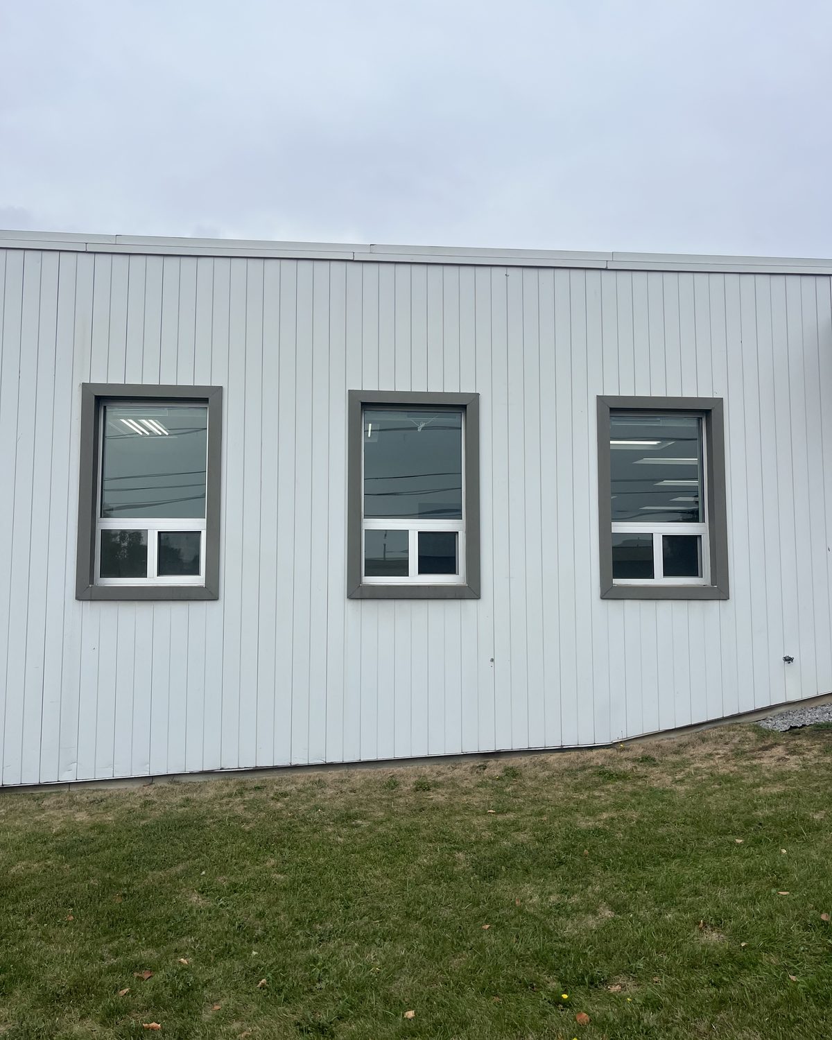 Three new sliding windows in grey surrounds on the white-clad wall of a commercial building on Sunrise Avenue, Toronto