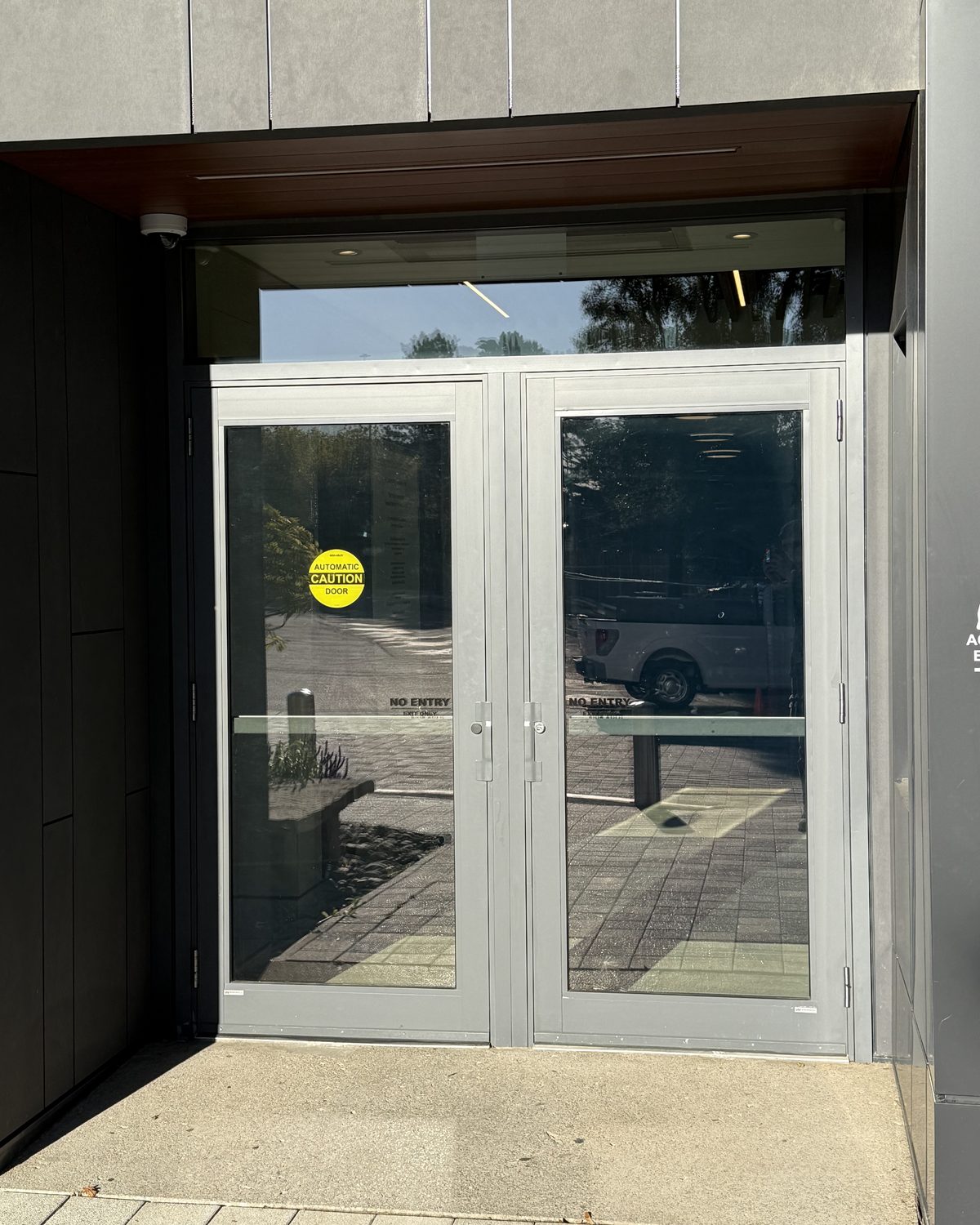 A pair of glazed aluminum entrance doors set into the dark cladding of Temple Sinai Congregation's west entrance in Toronto