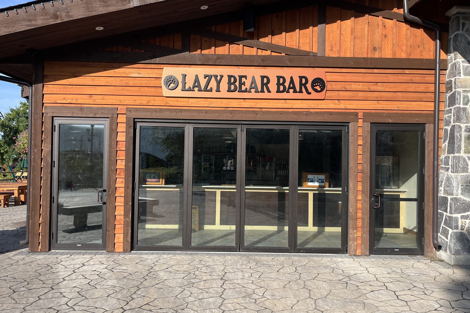 The Lazy Bear Bar front at Canada's Wonderland: a run of dark aluminum bi-fold doors between glazed side panels under the bar's sign