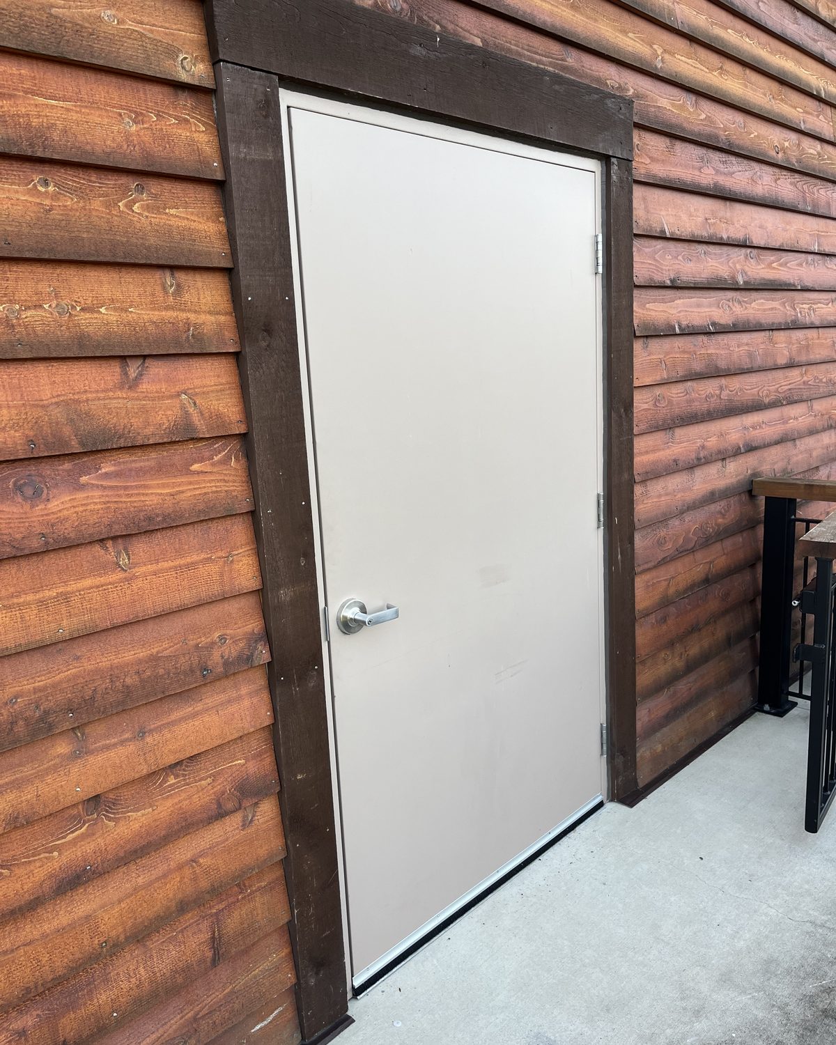 A light grey hollow metal door in a dark frame, set into the log-style timber cladding of Lazy Bear Lodge at Canada's Wonderland