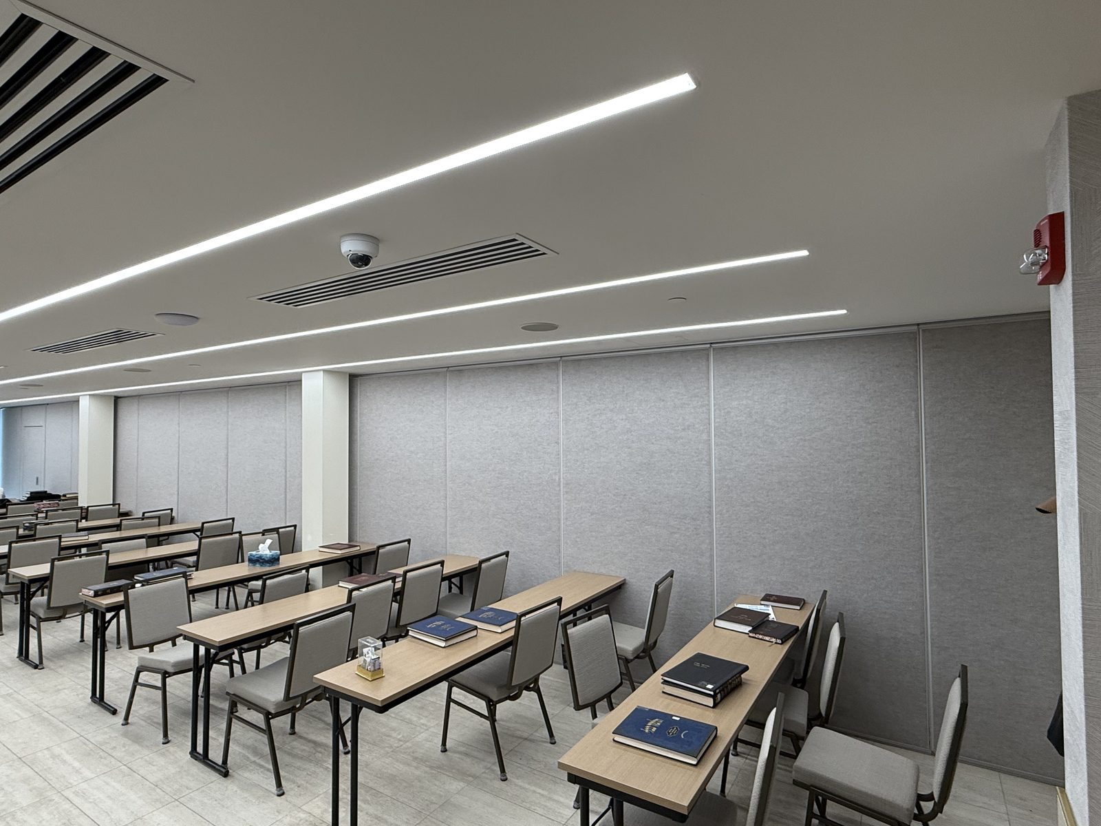 A closed operable wall of tall grey carpeted panels running across a classroom at the Eitz Chaim & Kollel School in Vaughan, with rows of desks and chairs in front of it, installed by Canuck Door Systems