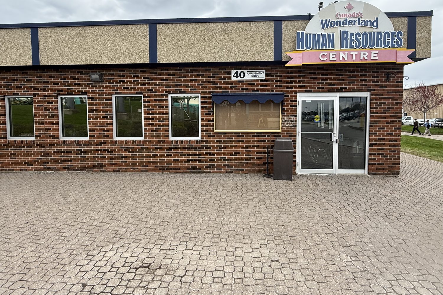 A single-storey brick building at Canada's Wonderland seen square-on, with an aluminum glass entrance door and sidelite at one end and a row of new windows along the wall